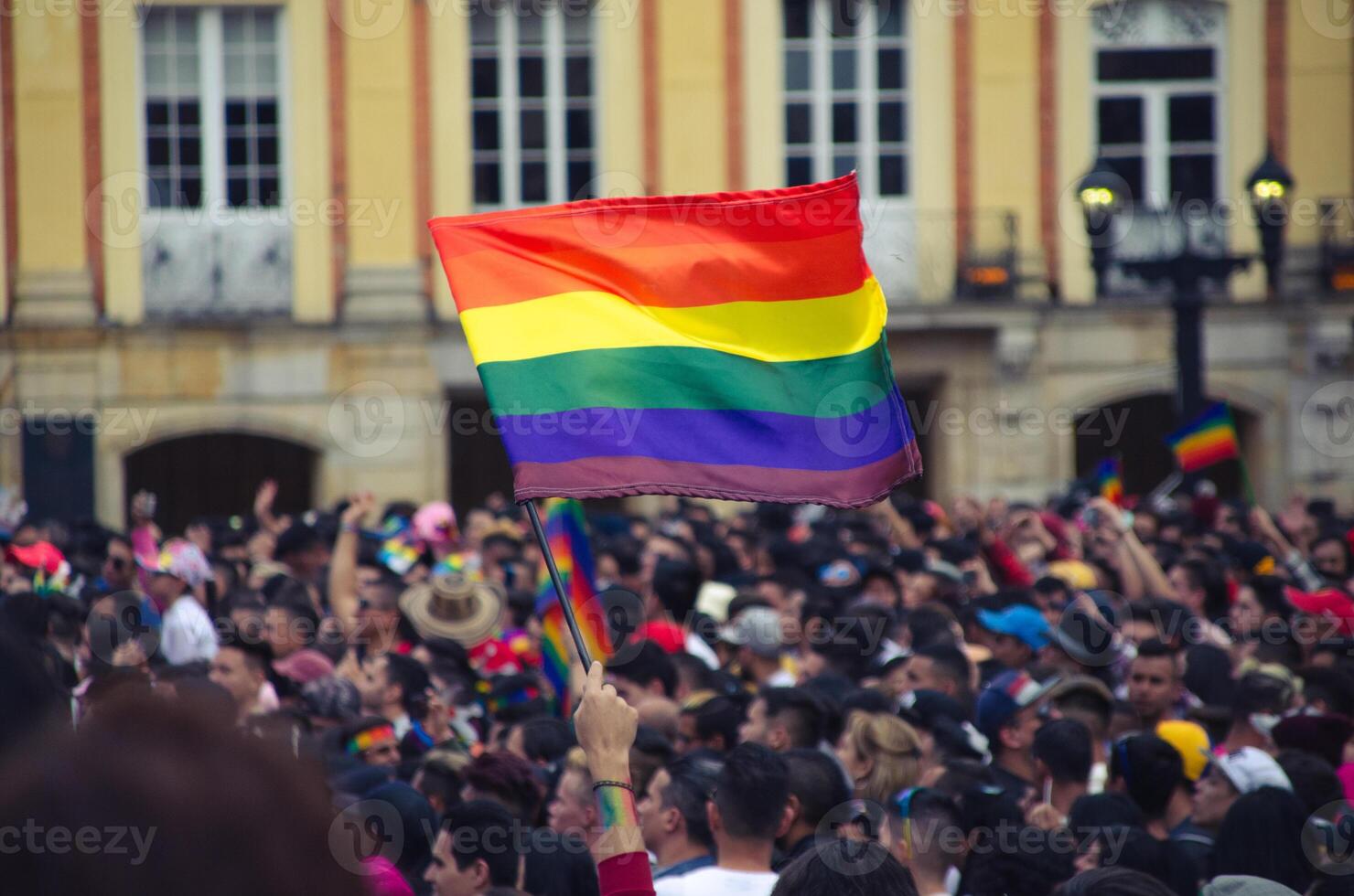 landscape shot of lgbti flag being waved at a demonstration full of people photo