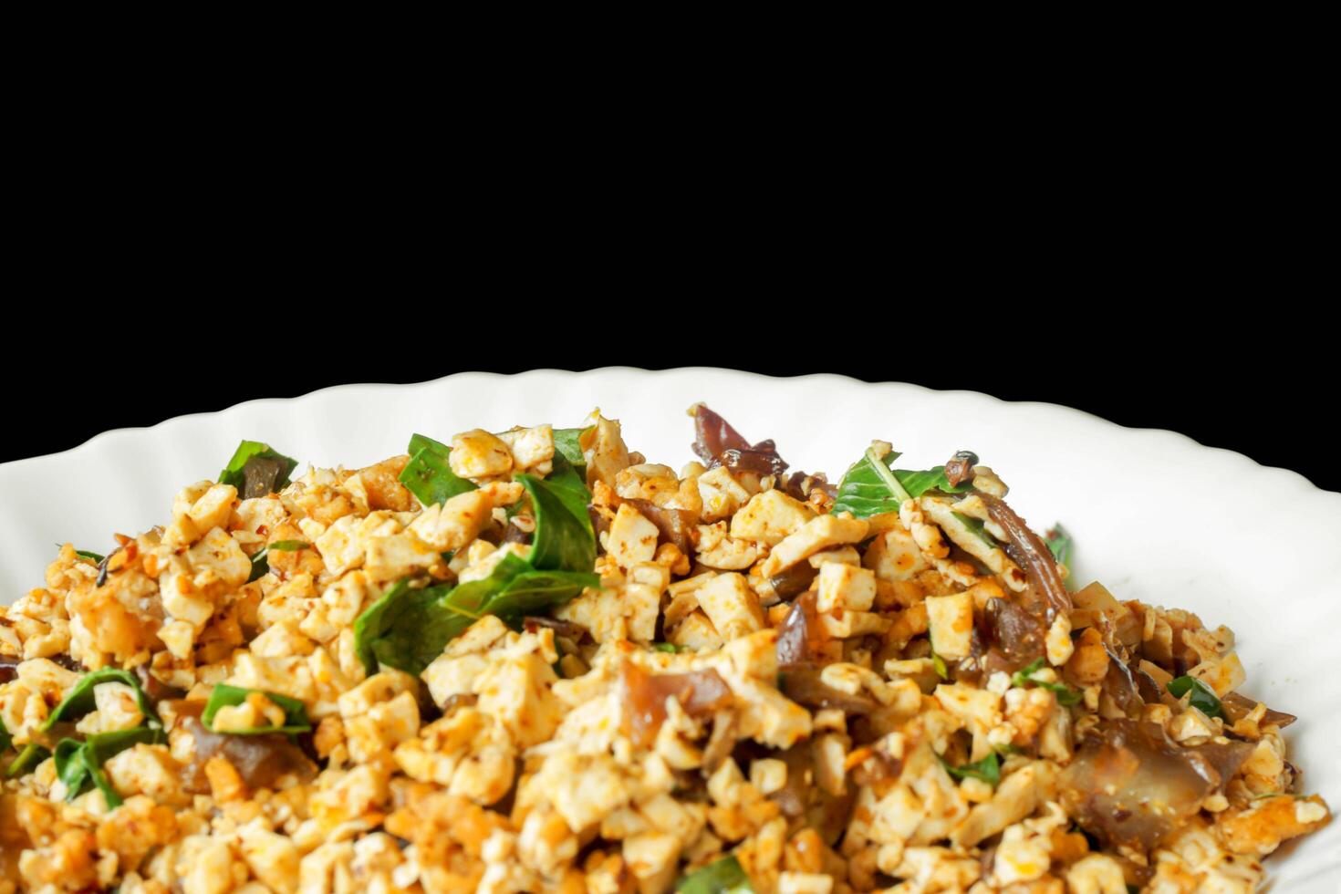 Closeup fusion vegan food in Thai northern style in white ceramic plate isolate on black background. Thai and Chinese people popular eaten vegan foods in Chinese vegetarian festival. photo