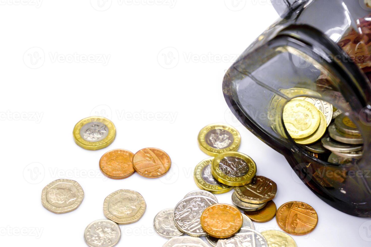 Top view and crop of British currency coins open from the piggy bank laid out scattered on right with copy space for texts and white background. photo