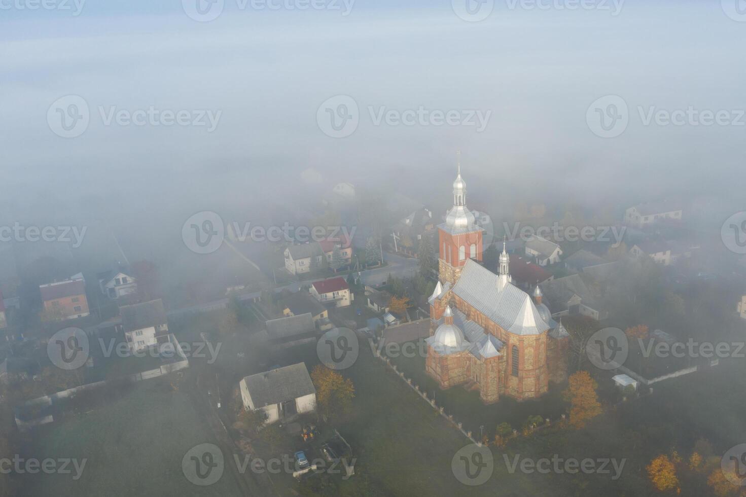 Surreal view of church almost completely hidden by fog photo