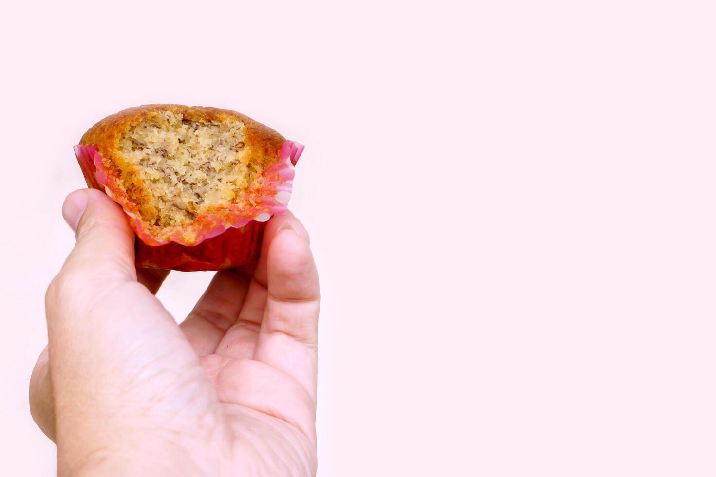 Hand holding Thai ancient eggs cupcake was eaten isolate on pink background with copy space for texts. photo