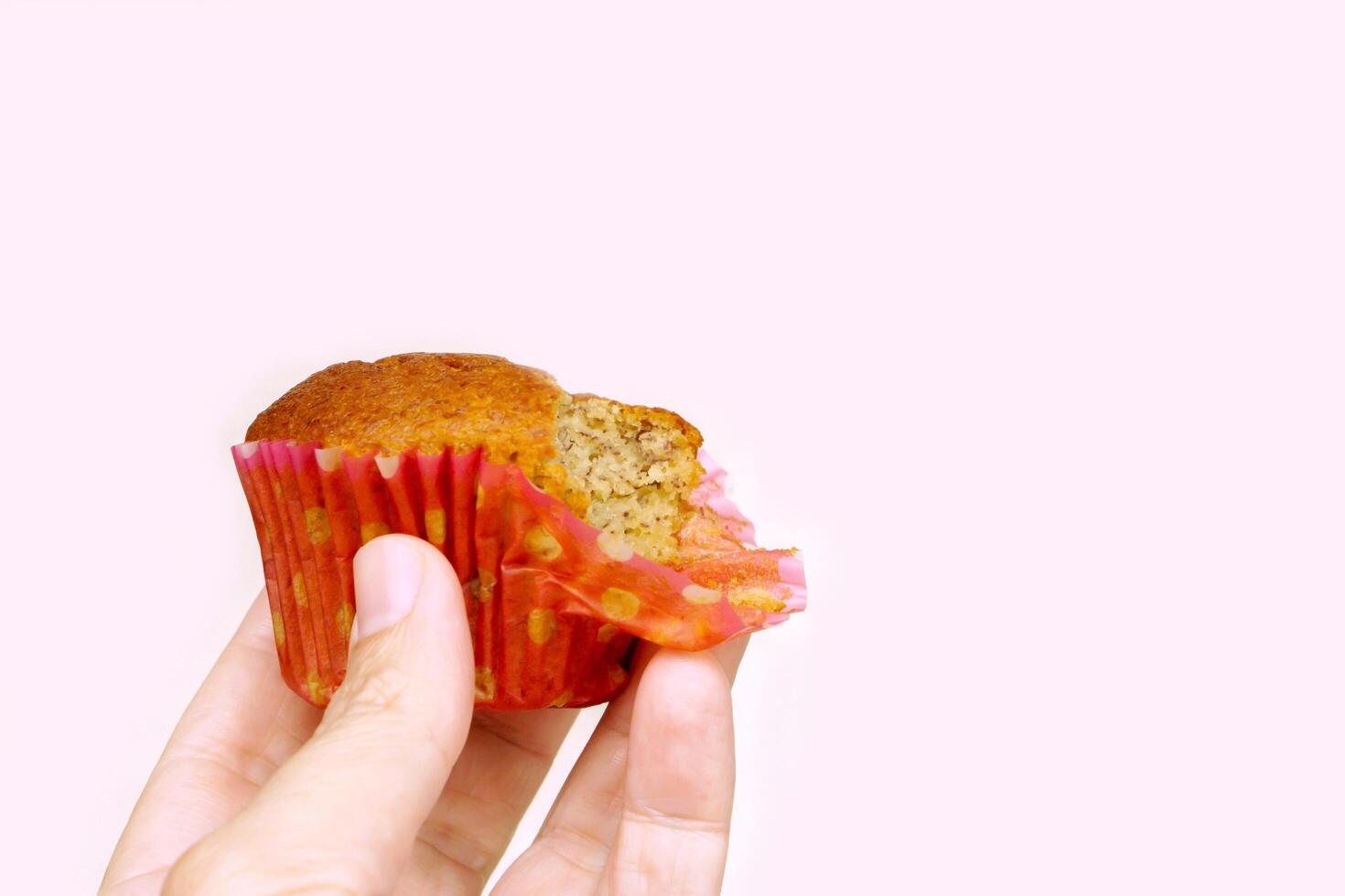 Closeup hand holding Thai ancient eggs cupcake was eaten isolate on pink background with copy space for texts. photo