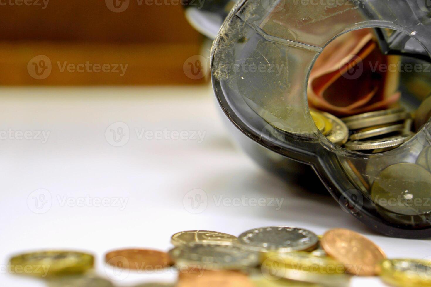 Closeup of British currency coins open from the piggy bank laid out scattered on white table and wooden background. photo