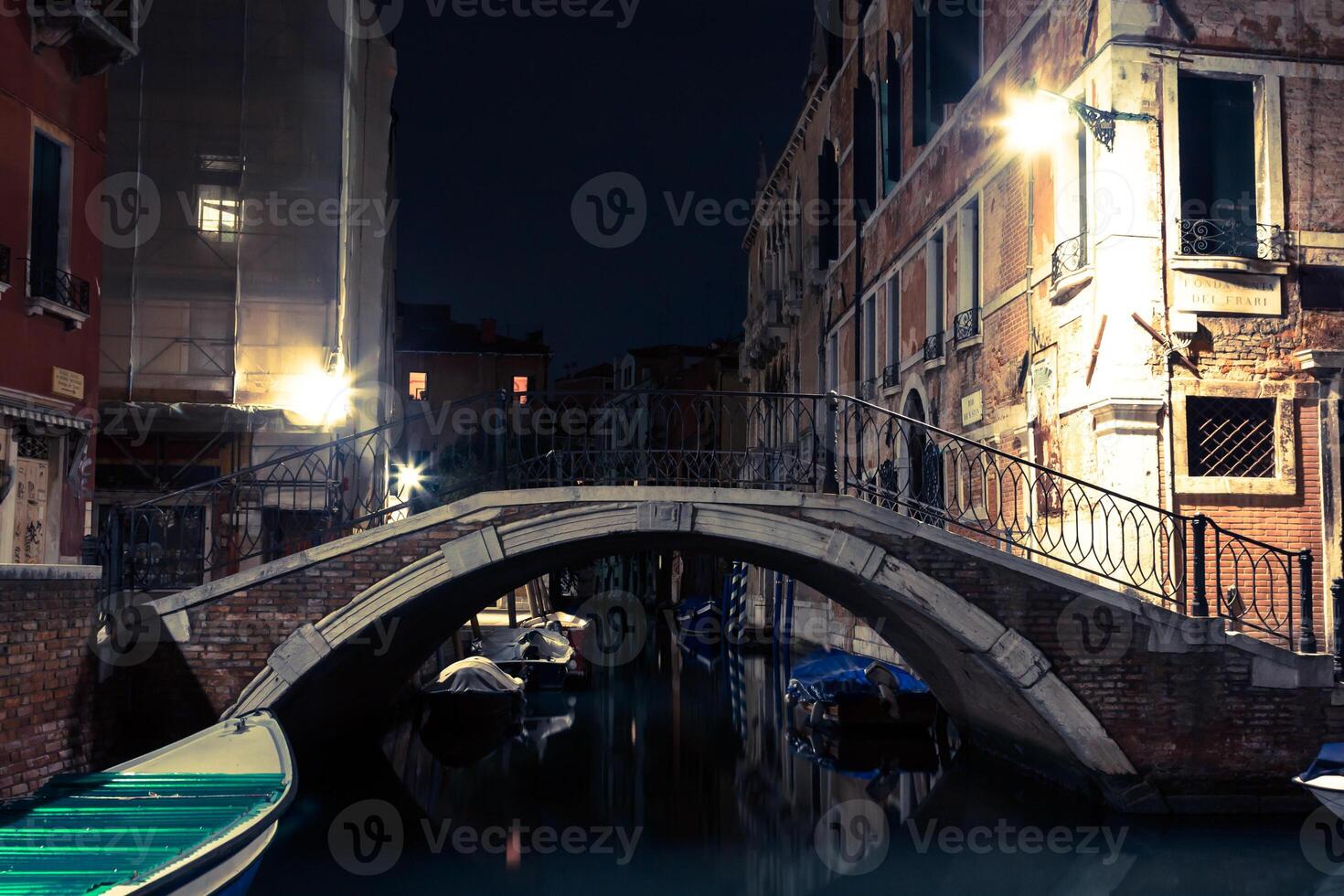 Venice canal late at night with street light illuminating bridge and houses photo