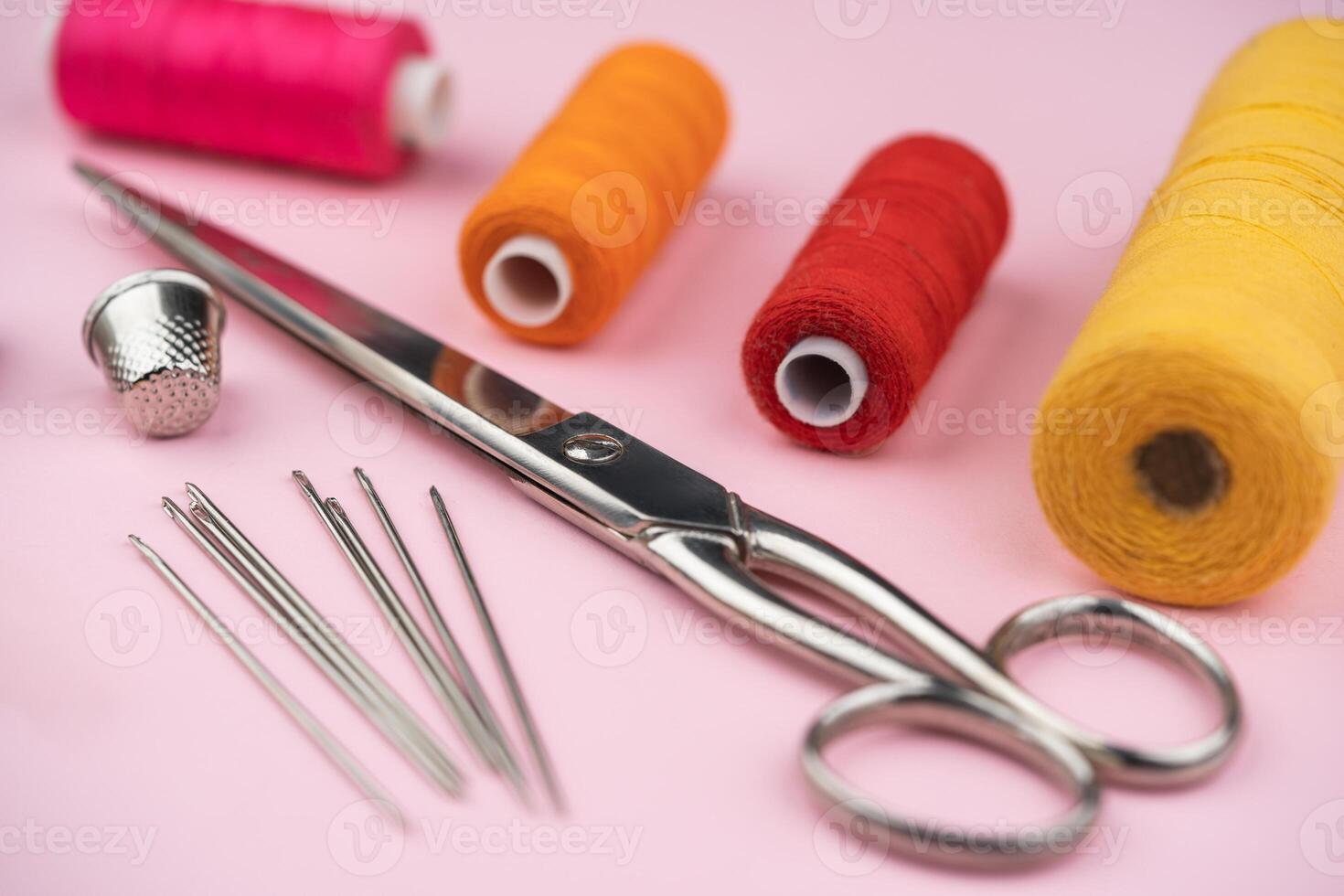 various tailor accessories and tools for tailoring on a pink background photo
