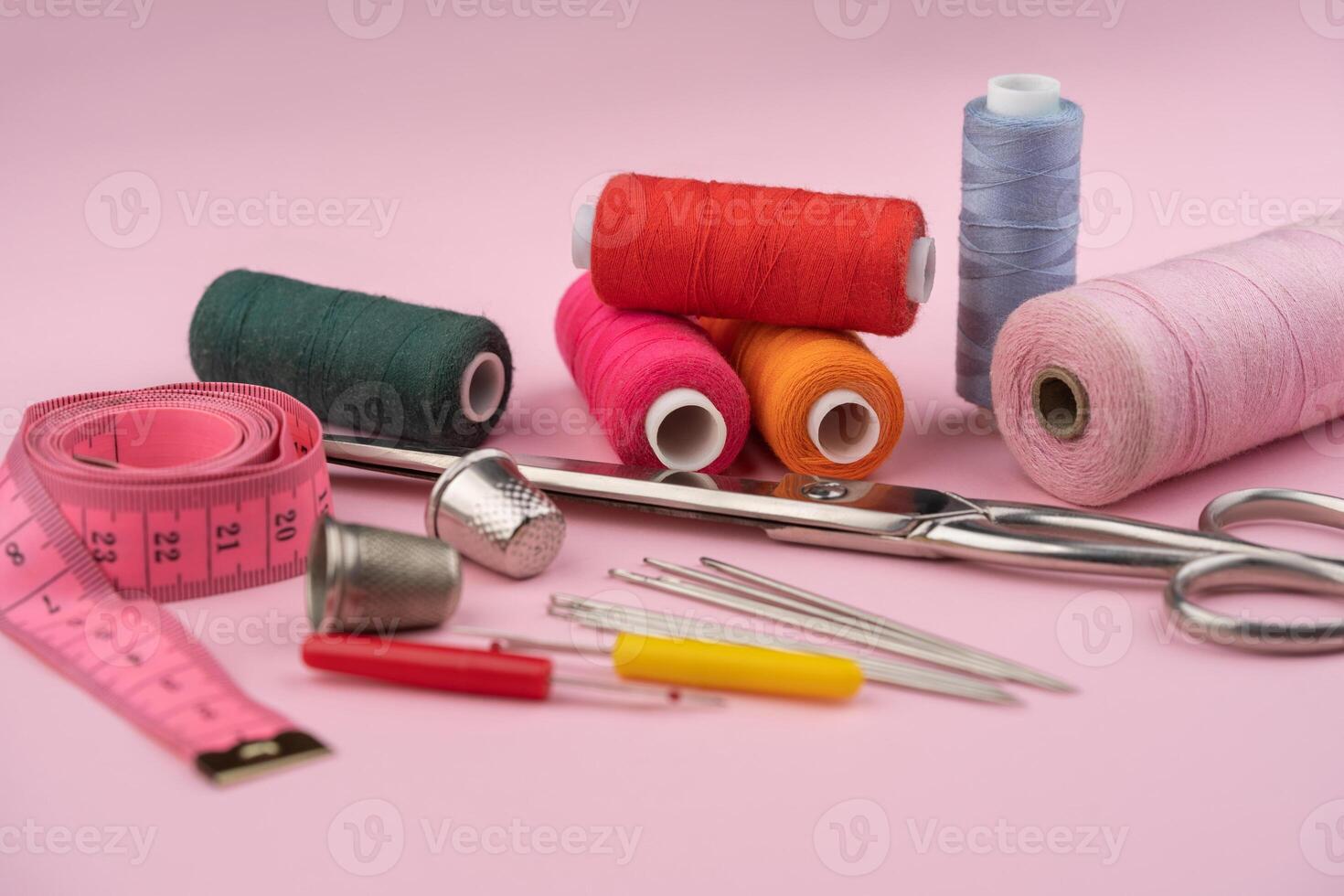 various tailor accessories and tools for tailoring on a pink background photo