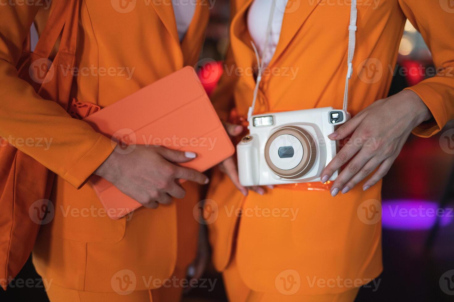 two female promoters in identical suits with a camera and a tablet photo