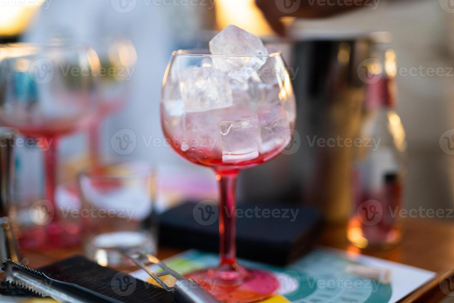 the bartender prepares an alcoholic cocktail by pouring ice cubes into a glass photo