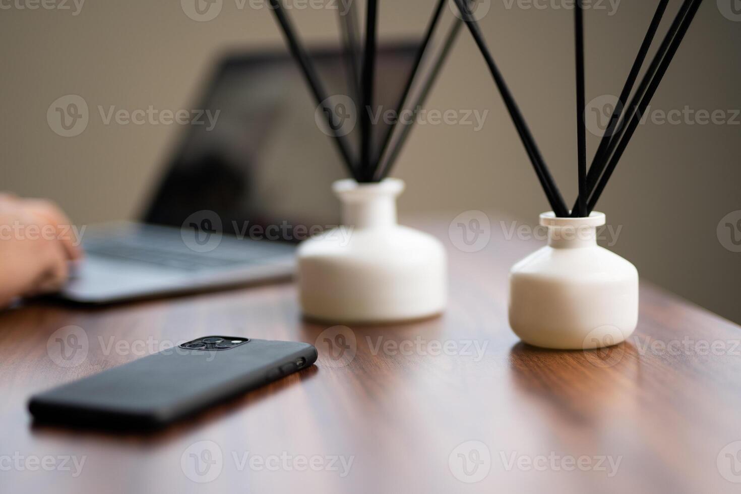 incense sticks in a vase on the table with phone and laptop photo