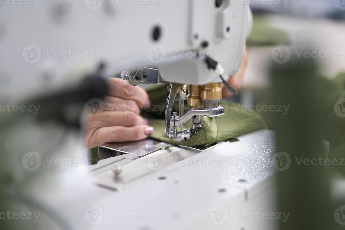 workers in an industrial garment factory sew clothes on sewing machine photo