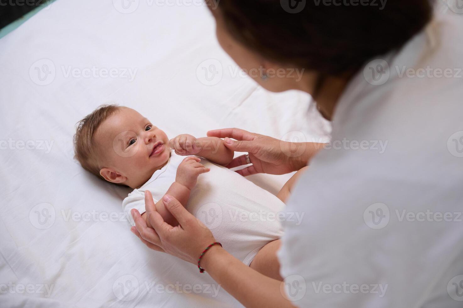 Loving mother cuddling baby, taking care of her newborn child, changing diapers, massaging feet and little tine hands. photo