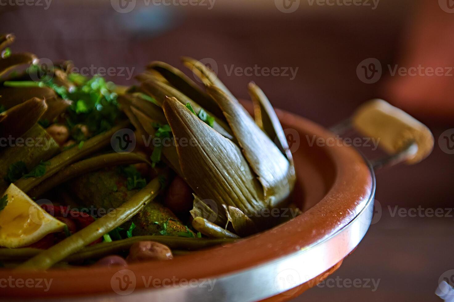 Extreme close-up photo for food blog of a delicious yummy meal with steamed artichokes in Moroccan tagine clay pot.