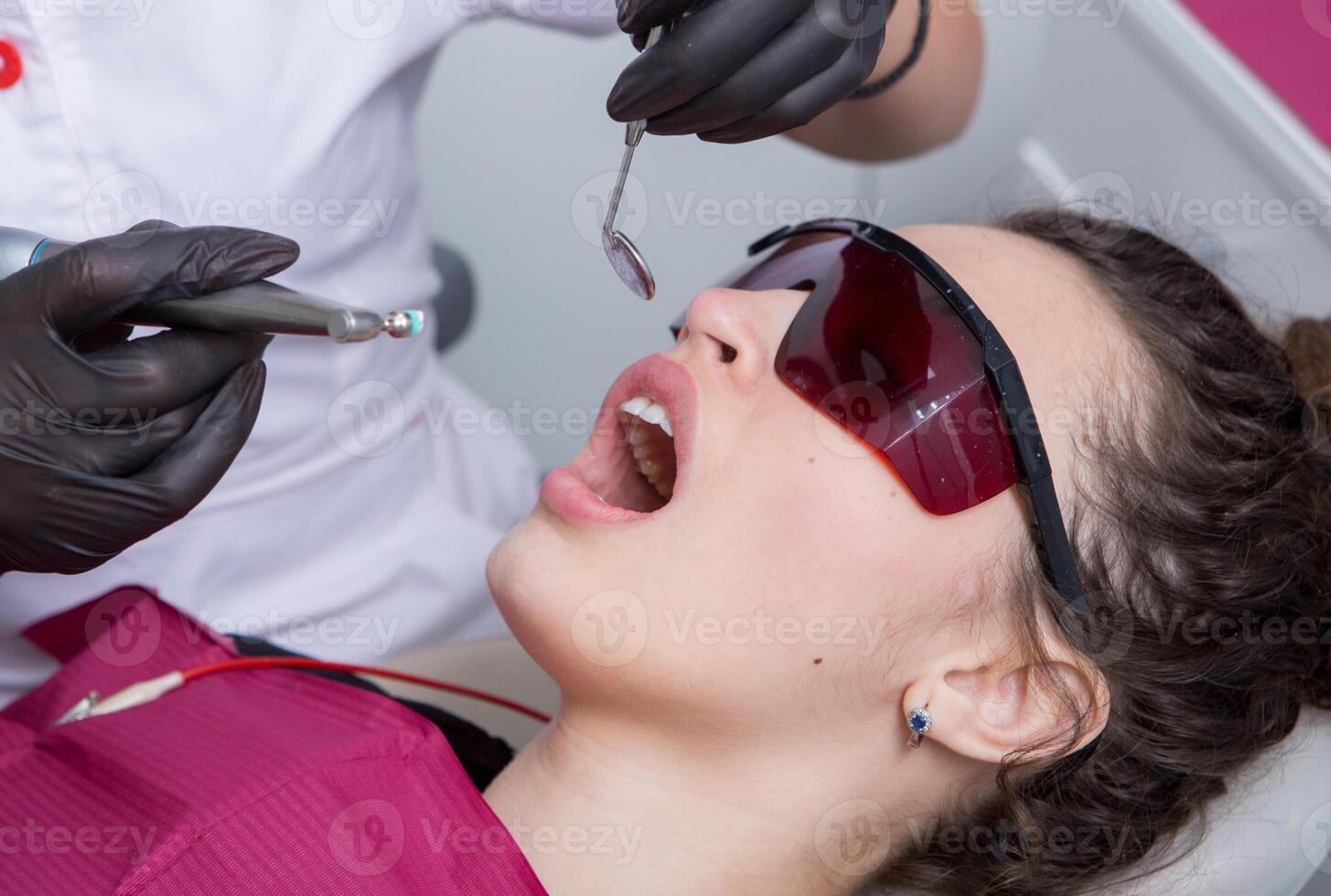 Dentist examining teeth of a young woman patient in a dental clinic. Dentistry concept. Dentist and patient in the dental office. photo