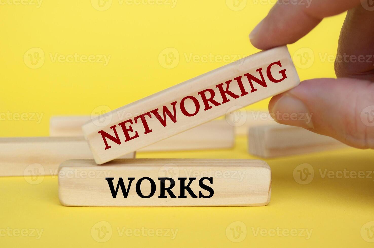 Hand placing wooden block on yellow cover with text - Networking works photo