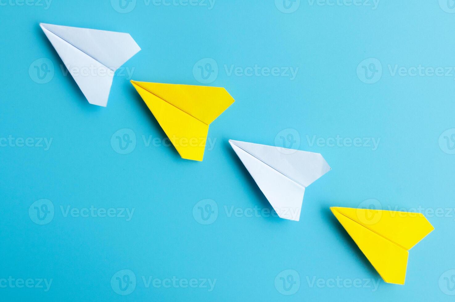 parte superior ver de blanco y amarillo papel aviones origami volador en azul antecedentes. foto