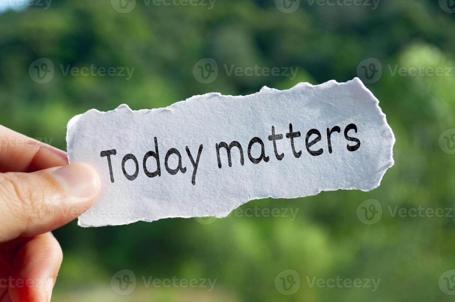 Today matters text on torn paper with hand holding on nature background photo