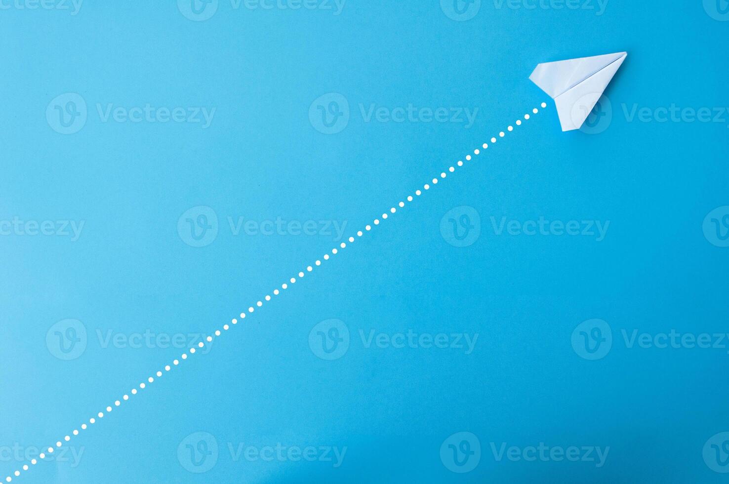 Top view of paper airplane with straight line dots on blue background photo