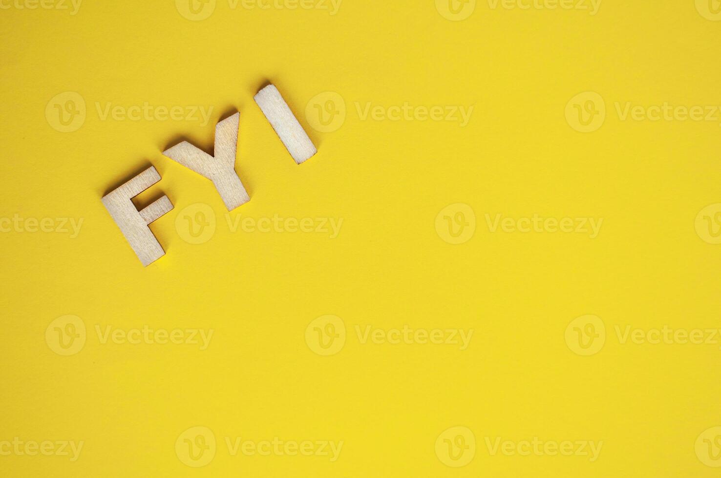 Top view of wooden FYI text on yellow background with customizable space for text photo