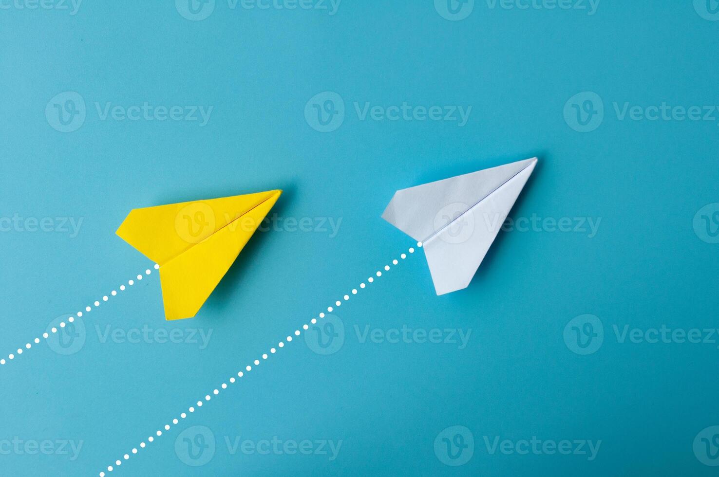 parte superior ver de papel avión - amarillo y blanco papel avión origami volador a un mismo dirección en azul antecedentes. foto