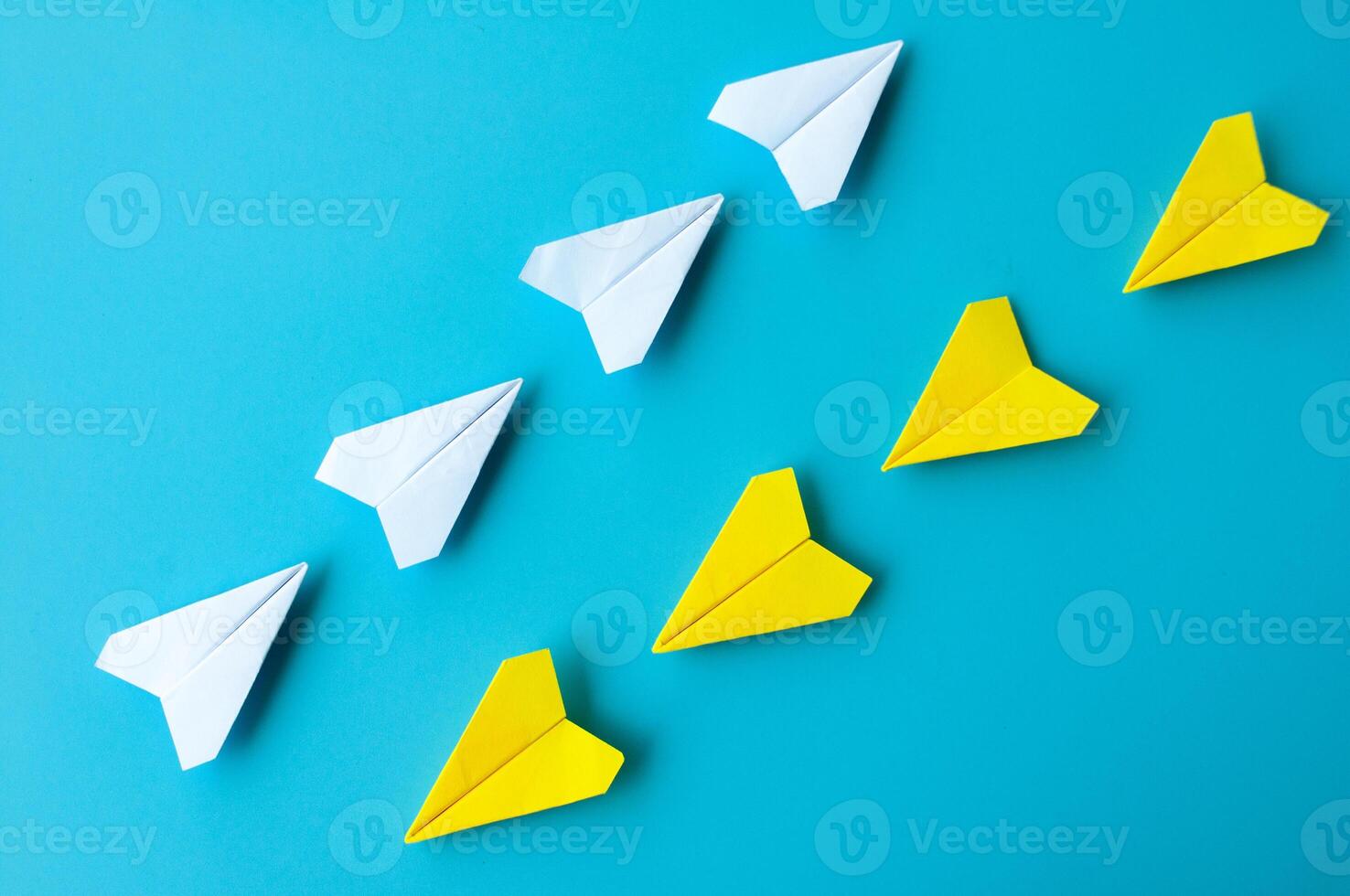 parte superior ver de un blanco y amarillo papel aviones origami volador a diferente dirección foto