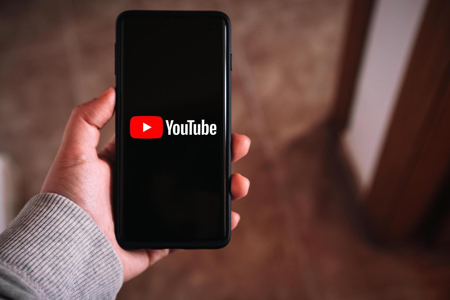 SPAIN, February 23, 2024, Woman holding smartphone with YouTube logo on screen. photo