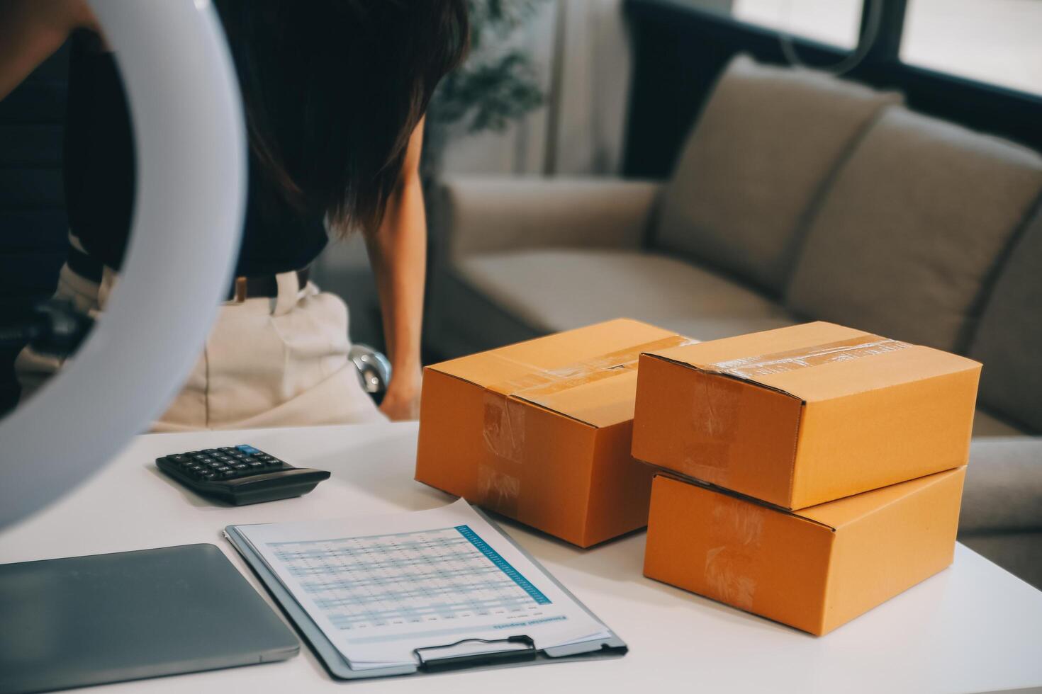 Fashion blogger concept, Young Asian women selling clothes on video streaming.Startup small business SME, using smartphone or tablet taking receive and checking in home office photo