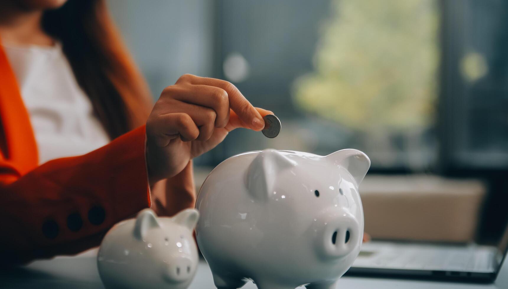 A young girl works at a laptop, writes a business development plan in a notebook, develops a strategy and makes calculations of earned funds. A woman puts her savings in a piggy bank. photo