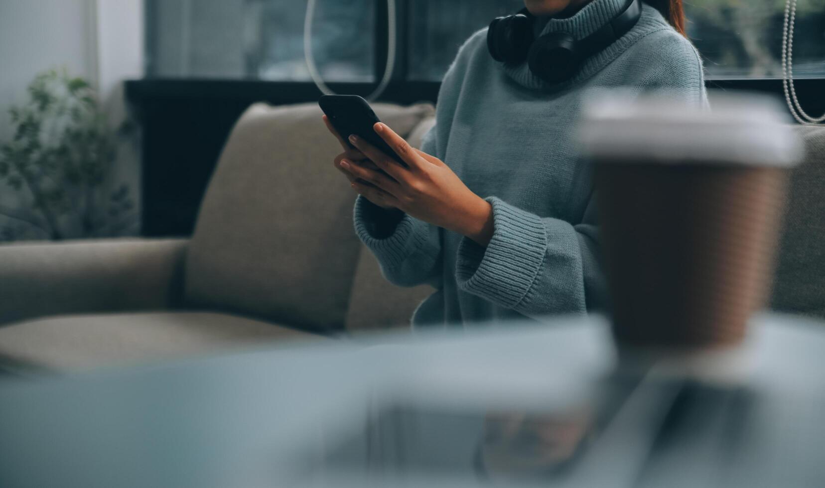 Happy pretty millennial Indian girl relaxing at home, resting in armchair, typing on smartphone, using online app, software, shopping on Internet, making video call. Mobile phone communication photo