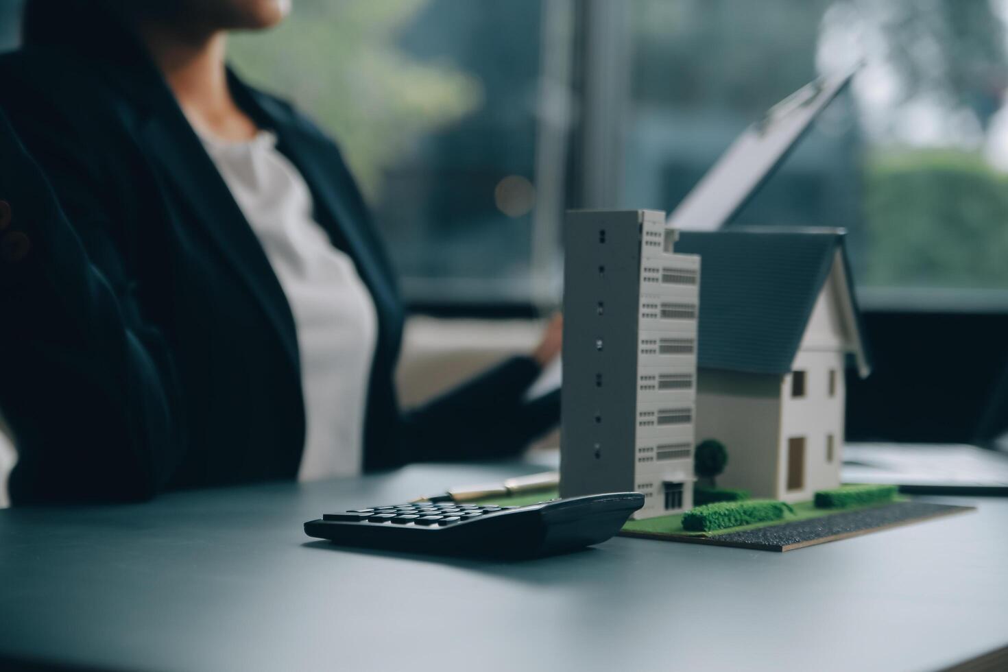 Close up realtor sit at table holds tiny house model, layout of cottage. Real estate purchase, new property, ownership, construction company make special offer to client, affordable dwelling concept photo