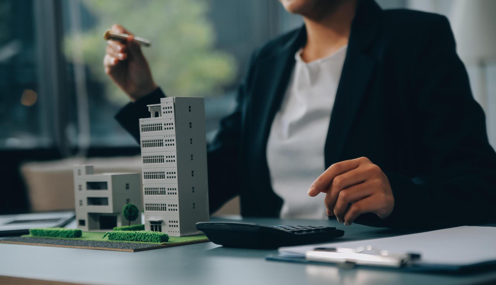 Close up realtor sit at table holds tiny house model, layout of cottage. Real estate purchase, new property, ownership, construction company make special offer to client, affordable dwelling concept photo