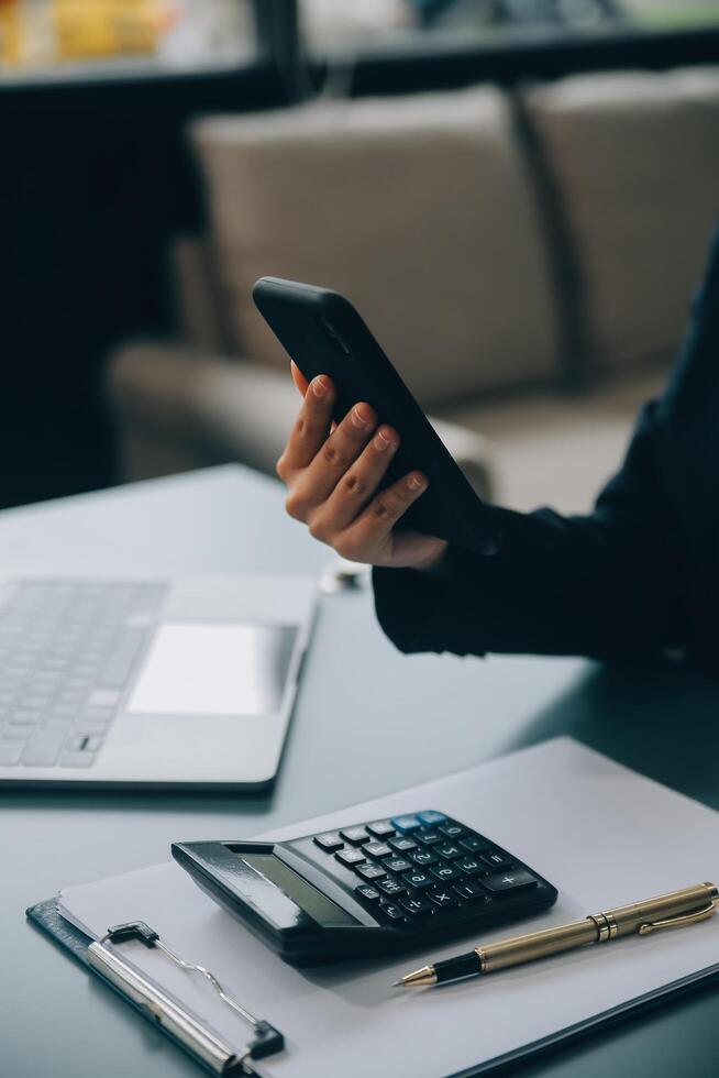 Hispanic businesswoman in formal attire in her office happy and cheerful while using smartphones and working. Young businesswoman using apps on cell phones, reading news, fast connection photo