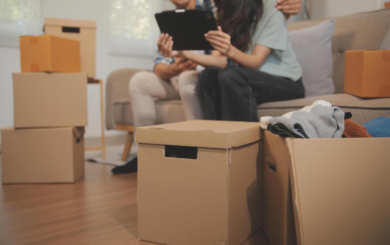 Two Asian blogger showing clothes in front of the camera to recording vlog video live streaming at her shop. Online Shopping Cart notion. on sofa at home photo