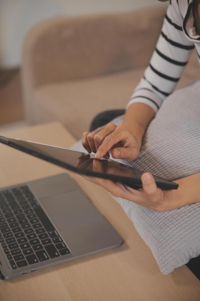 Young attractive asian woman resting using browsing tablet computer on sofa at home, happy girl sitting on couch relax reading digital gadget with excited, communication and lifestyle concept. photo