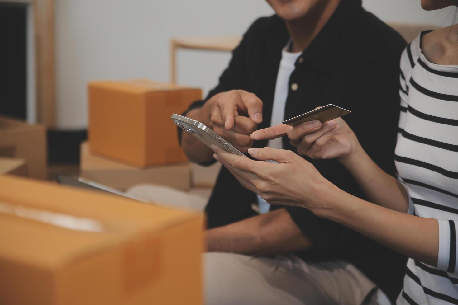 Two Asian blogger showing clothes in front of the camera to recording vlog video live streaming at her shop. Online Shopping Cart notion. on sofa at home photo