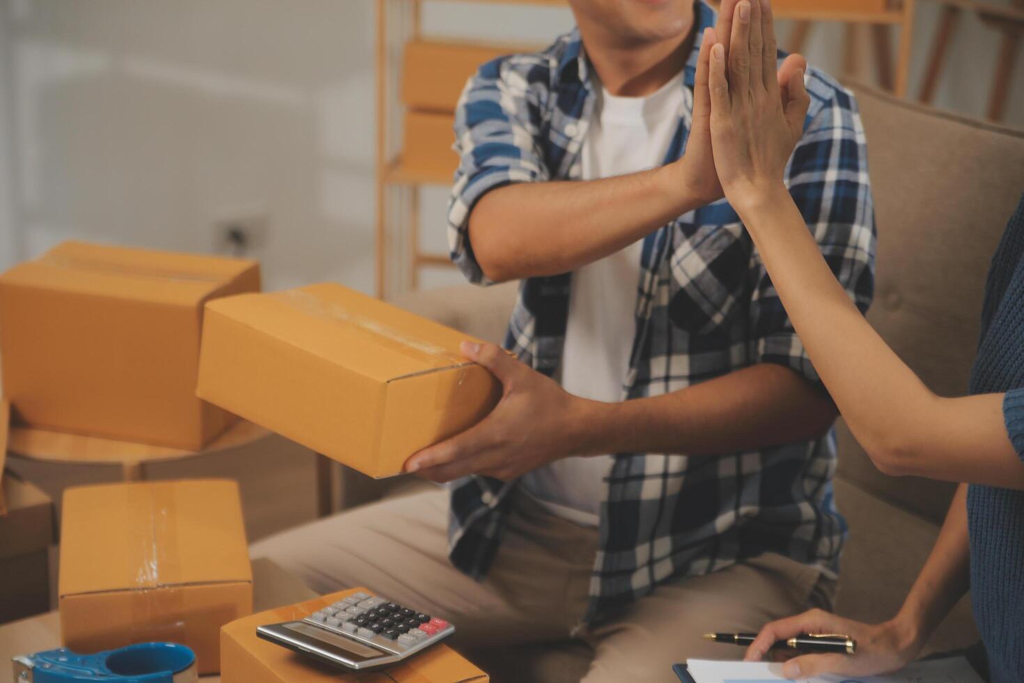 Two Asian blogger showing clothes in front of the camera to recording vlog video live streaming at her shop. Online Shopping Cart notion. on sofa at home photo