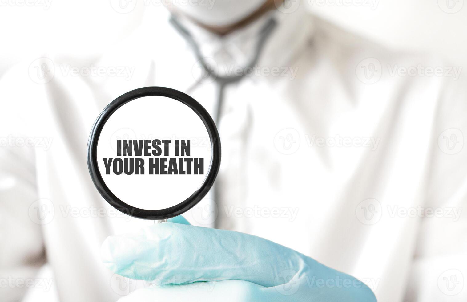 Doctor holding a stethoscope with text INVEST IN YOUR HEALTH, medical concept photo