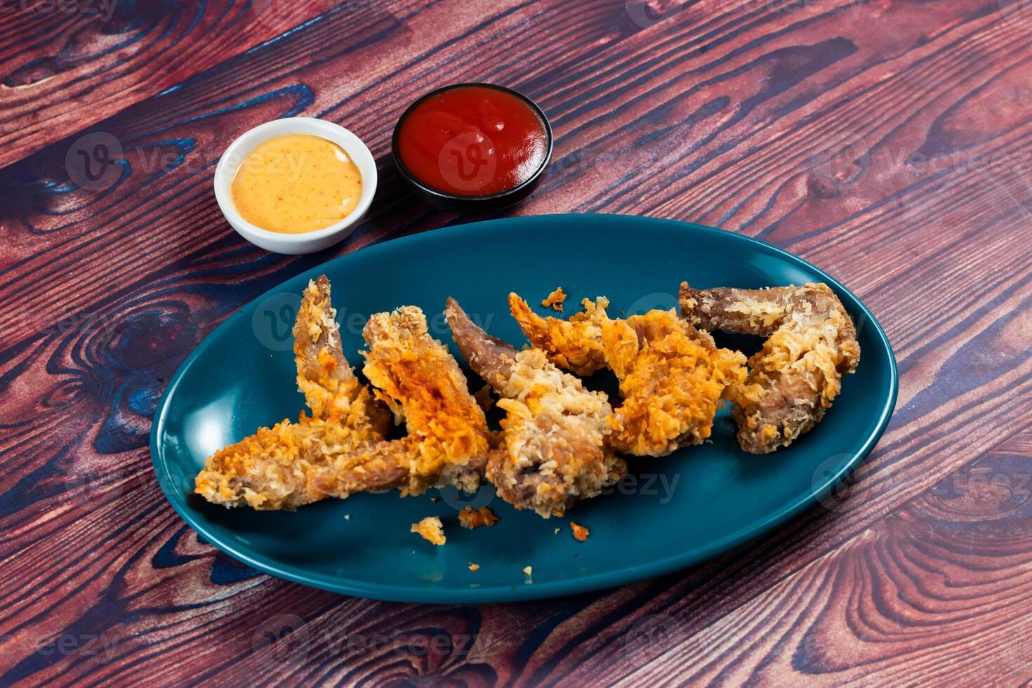 Crispy chicken wings with tomato sauce and mayo dip isolated on cutting board side view of fastfood photo