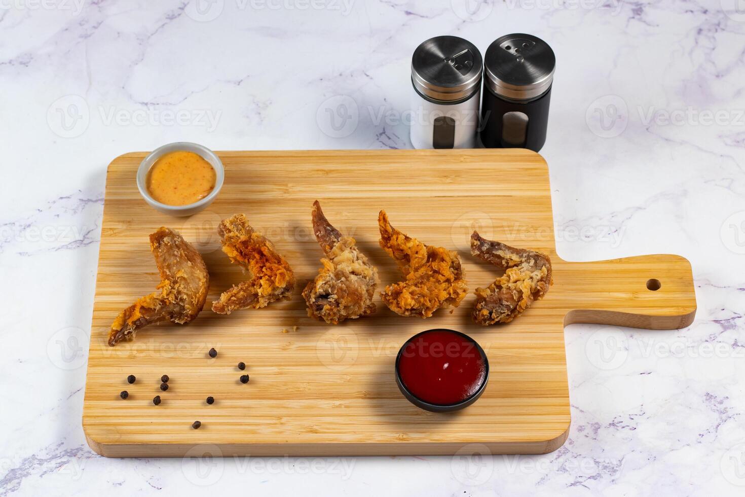 Crispy chicken wings with tomato sauce and mayo dip isolated on cutting board side view of fastfood photo