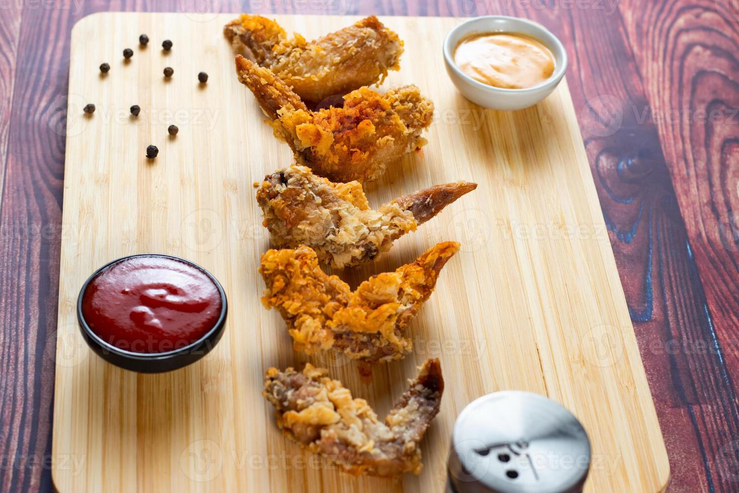 Crispy chicken wings with tomato sauce and mayo dip isolated on cutting board side view of fastfood photo