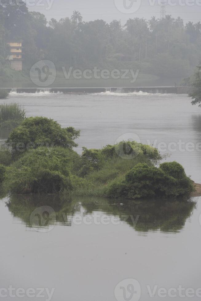 A landscape view of a calm river with green trees and mountain in India photo