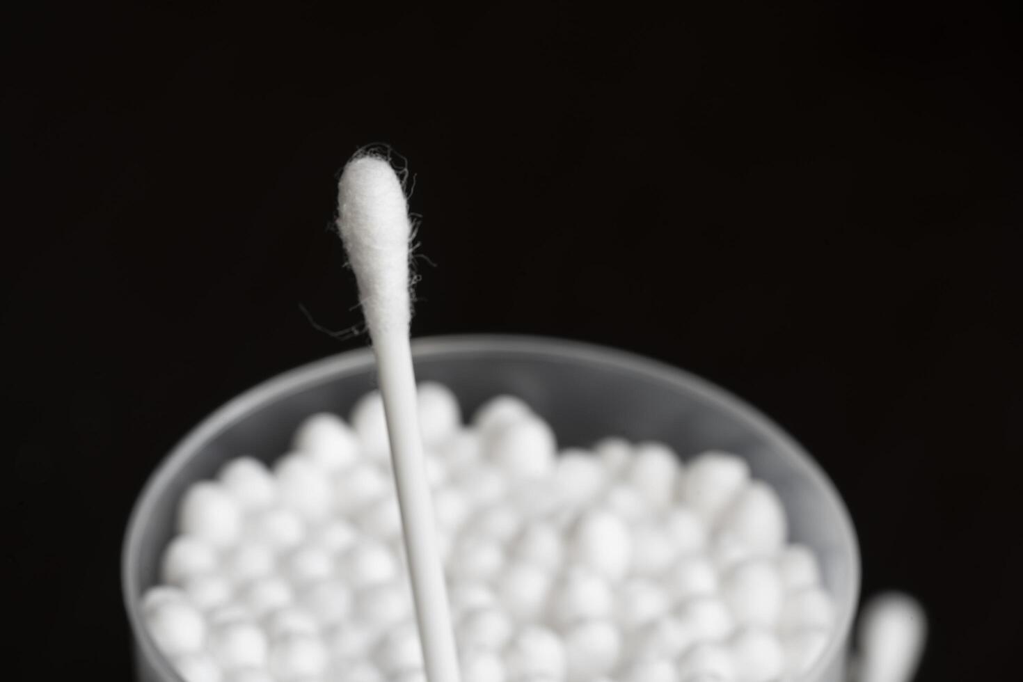 Macro view of white cotton ear cleaning buds arranged in black background nicely in a container photo