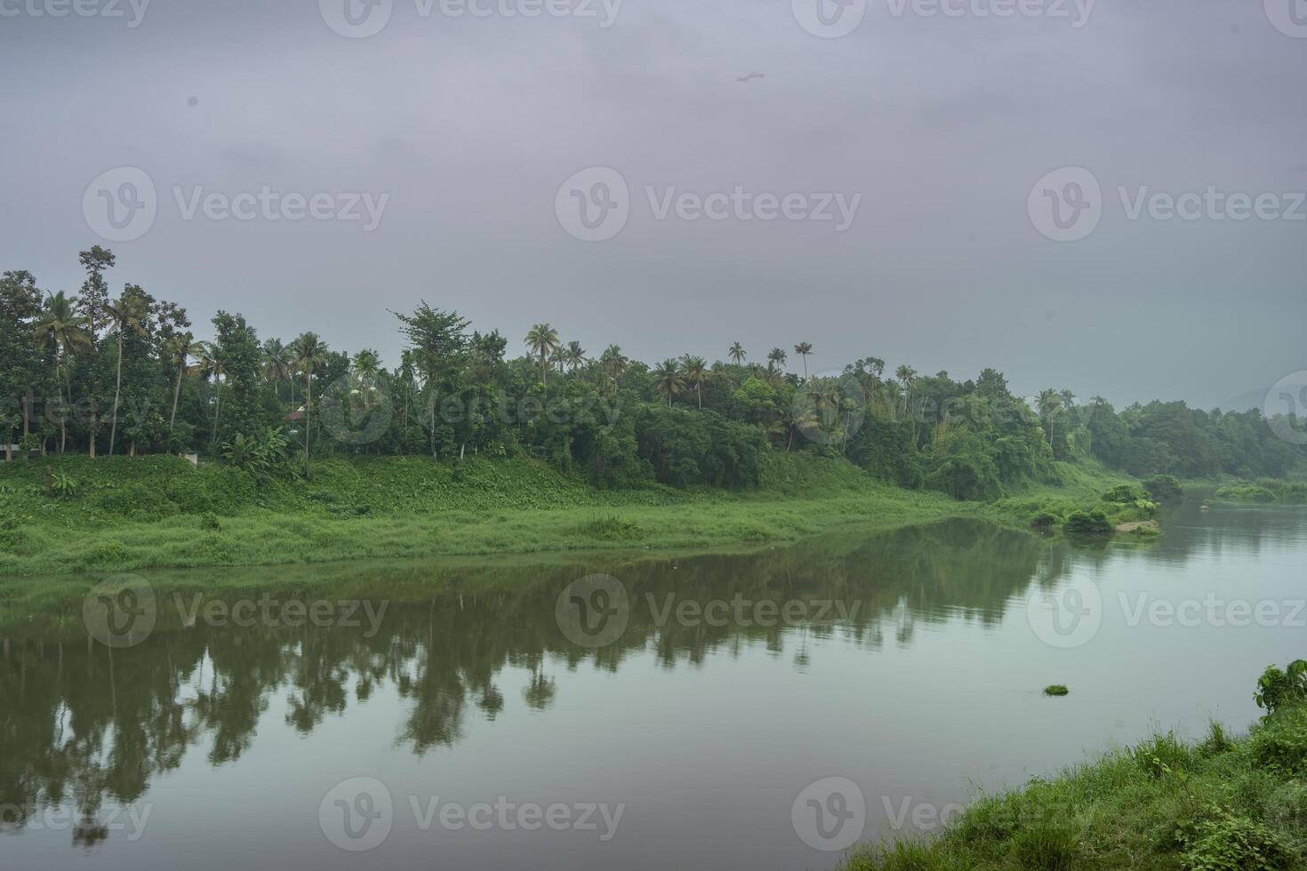 A landscape view of a calm river with green trees and mountain in India photo