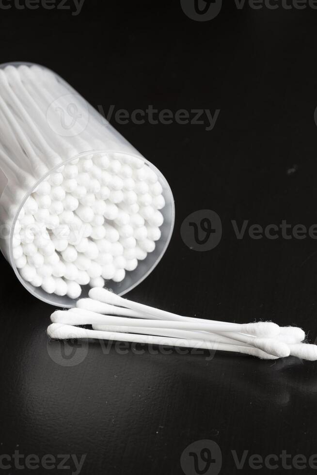 Macro view of white cotton ear cleaning buds arranged in black backgroud nicely in a container photo