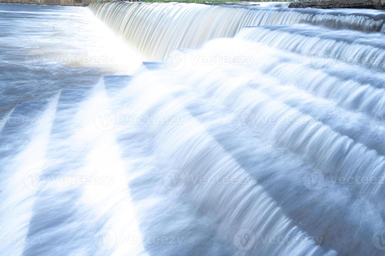un puro blanco cascada antecedentes formado en el río a través de cheque represa foto