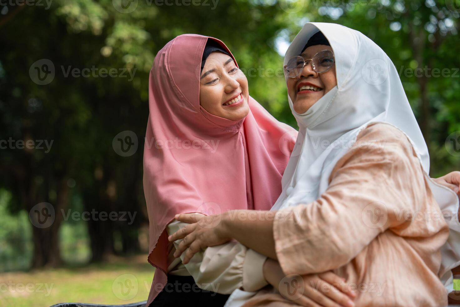 Muslim careful caregiver or nurse taking care of the patient in the hospital park. Happy Muslim mother in hijab hugging daughter. Concept of Savings and Senior Health Insurance, a Happy Family photo