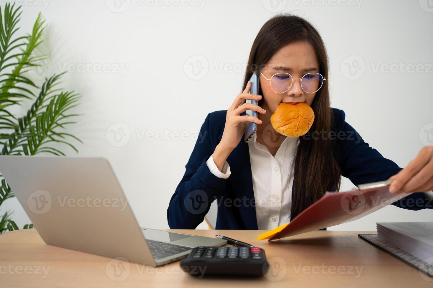 ocupado y cansado mujer de negocios comiendo un pan y Leche para almuerzo a el escritorio oficina y trabajando a entregar financiero declaraciones a un jefe. sobrecargado de trabajo y insalubre para Listo comidas, agotamiento concepto. foto