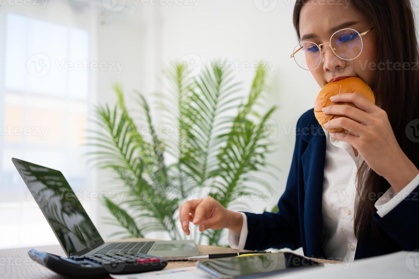 Busy and tired businesswoman eating Bread and milk for lunch at the Desk office and working to deliver financial statements to a boss. Overworked and unhealthy for ready meals, burnout concept. photo