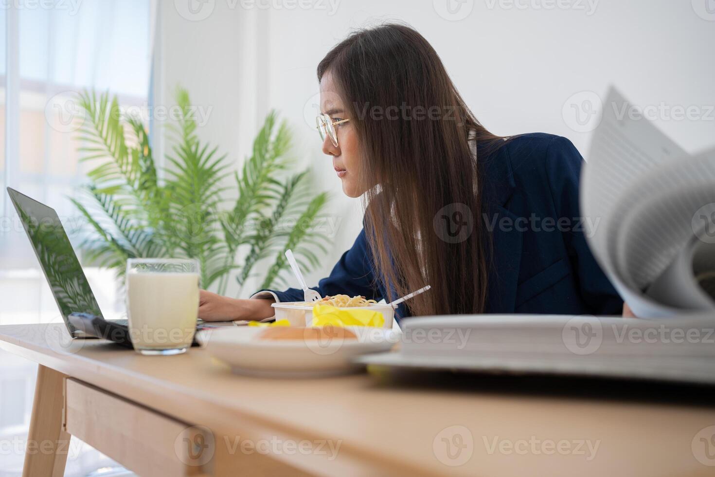 Busy and tired businesswoman eating spaghetti for lunch at the Desk office and working to deliver financial statements to a boss. Overworked and unhealthy for ready meals, burnout concept. photo