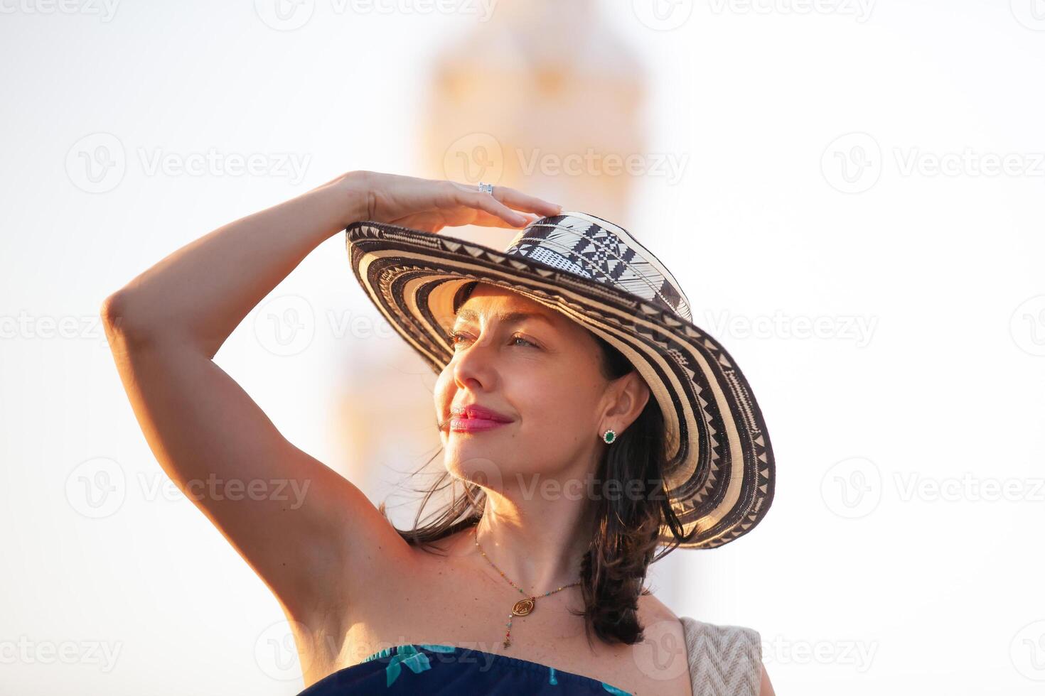 hermosa mujer vistiendo el tradicional Colombiana sombrero llamado sombrero vueltiao a el reloj torre en el histórico calles de el cartagena Delaware indios amurallado ciudad foto