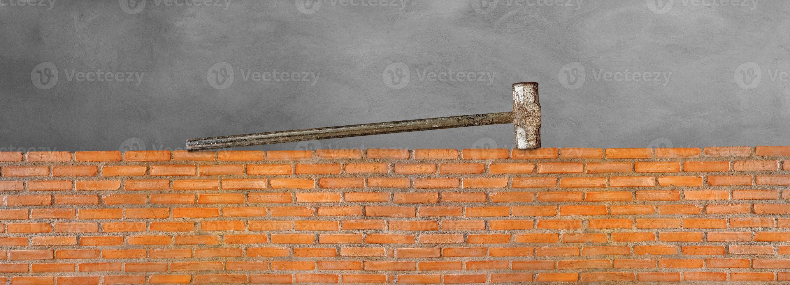 Pound hammer on red brick wall, cement background photo